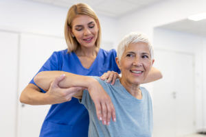 Doctor examining treating injured shoulder of senior patient