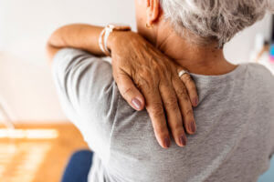 An elderly woman feeling shoulder pain.